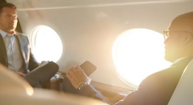 Two businessmen sitting down on private jet