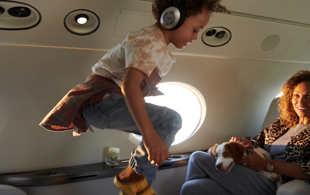 Child jumping inside of private jet, mom in background